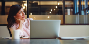 Women Staring Away While Sitting at Her Desk with Laptop Opened - Global Solution Services